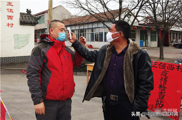 邹平市孙镇王伍西村疫情检查站人员对进村村民进行体温测量.