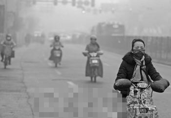 2日早晨,一名戴口罩的济南市民骑车行驶在雾霾笼罩的大街上。　本报记者　戴伟　摄