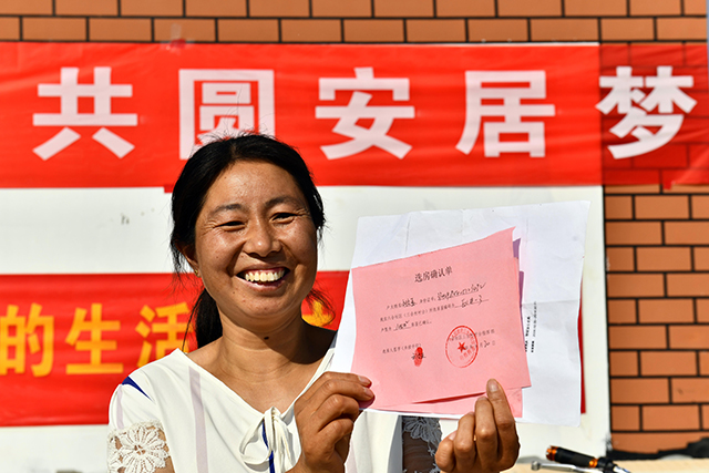 在菏泽市鄄城县旧城镇六合社区（三合村村台），王庄村村民在展示自己的选房确认单（2020年9月20日摄）。