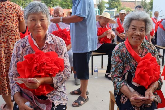 鱼台县王庙镇大奚村村民缪士花（左）和聂继英领到“孝心养老金”后开心不已