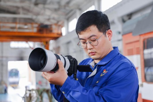 图为钮圣杰在机车检修库房拍摄作业场景