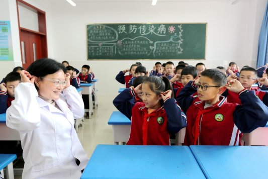 2023年3月1日，在山东省邹平市韩店镇中心小学，张爱萍正在教学生做耳朵保健操。