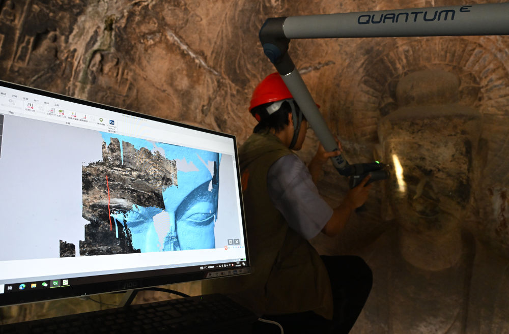 2025年4月9日,武汉大学文化遗产智能计算实验室团队成员在魏字洞使用关节臂扫描仪对佛像进行数字化扫描。图片来源新华社