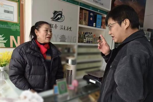 图为专卖执法人员上门为老年零售户梳理经营问题
