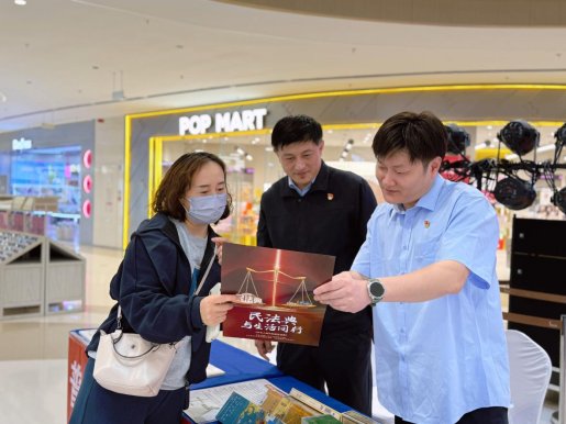 图二图为普法志愿者（右一、右二）宣传民法典知识