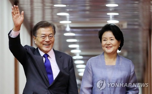 7月2日下午，在首尔机场，韩国总统文在寅(左)和第一夫人金正淑抵达首尔后挥手致意。(韩联社)
