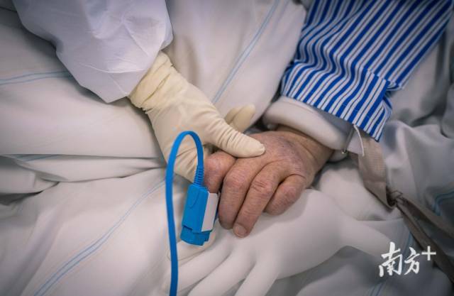 广东支援湖北荆州医疗队队员握紧病人的手，给予他坚持下去的力量。