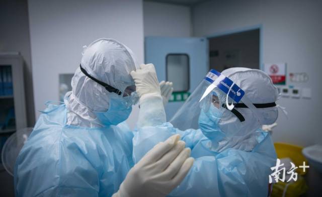 准备进入ICU病房前，医疗队队员帮助同伴调整护目镜。