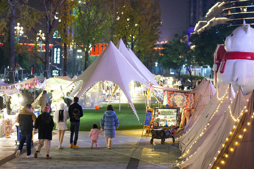 霓虹点缀中的集市，游客络绎不绝。郭旭摄