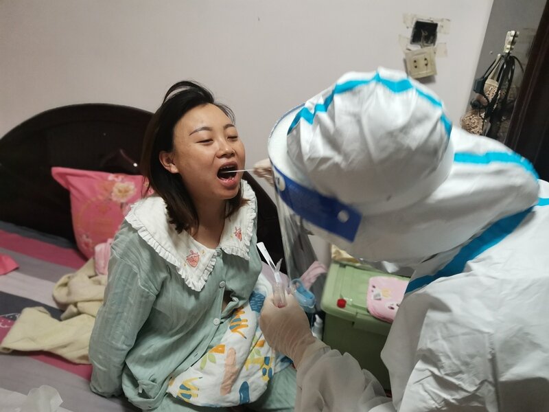 两名医护人员一遍遍为老人示范着张嘴,拆棉签,采集咽拭子的动作