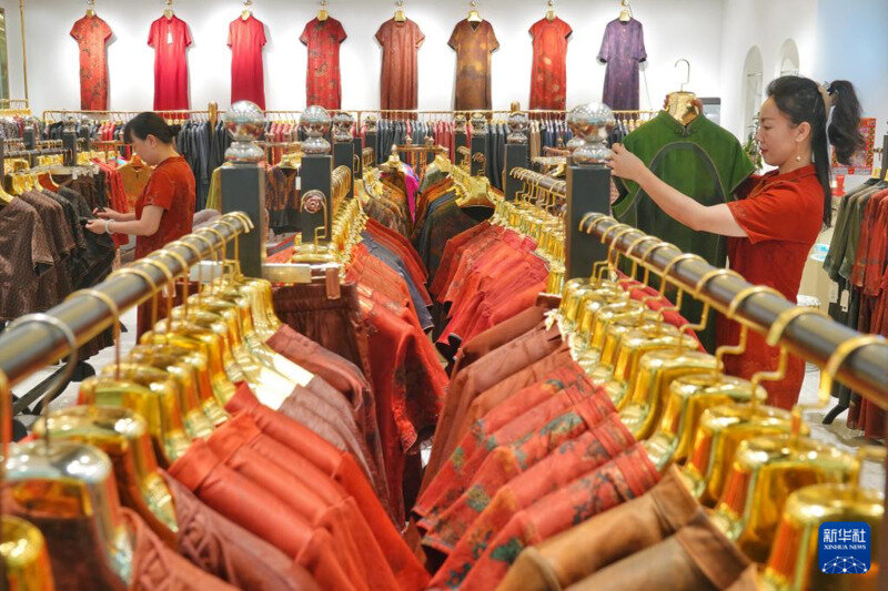 5月15日,在青岛市即墨服装批发市场,一家旗袍专卖店店员在整理衣架